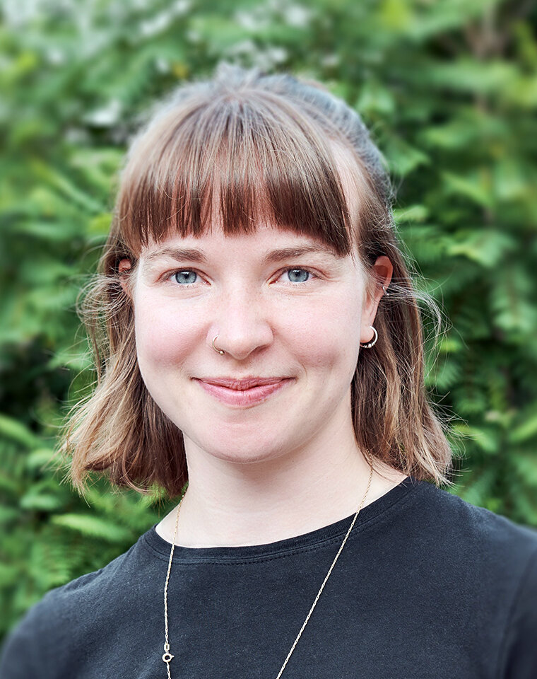 Paula Unland, Portrait vor grüner Hecke.