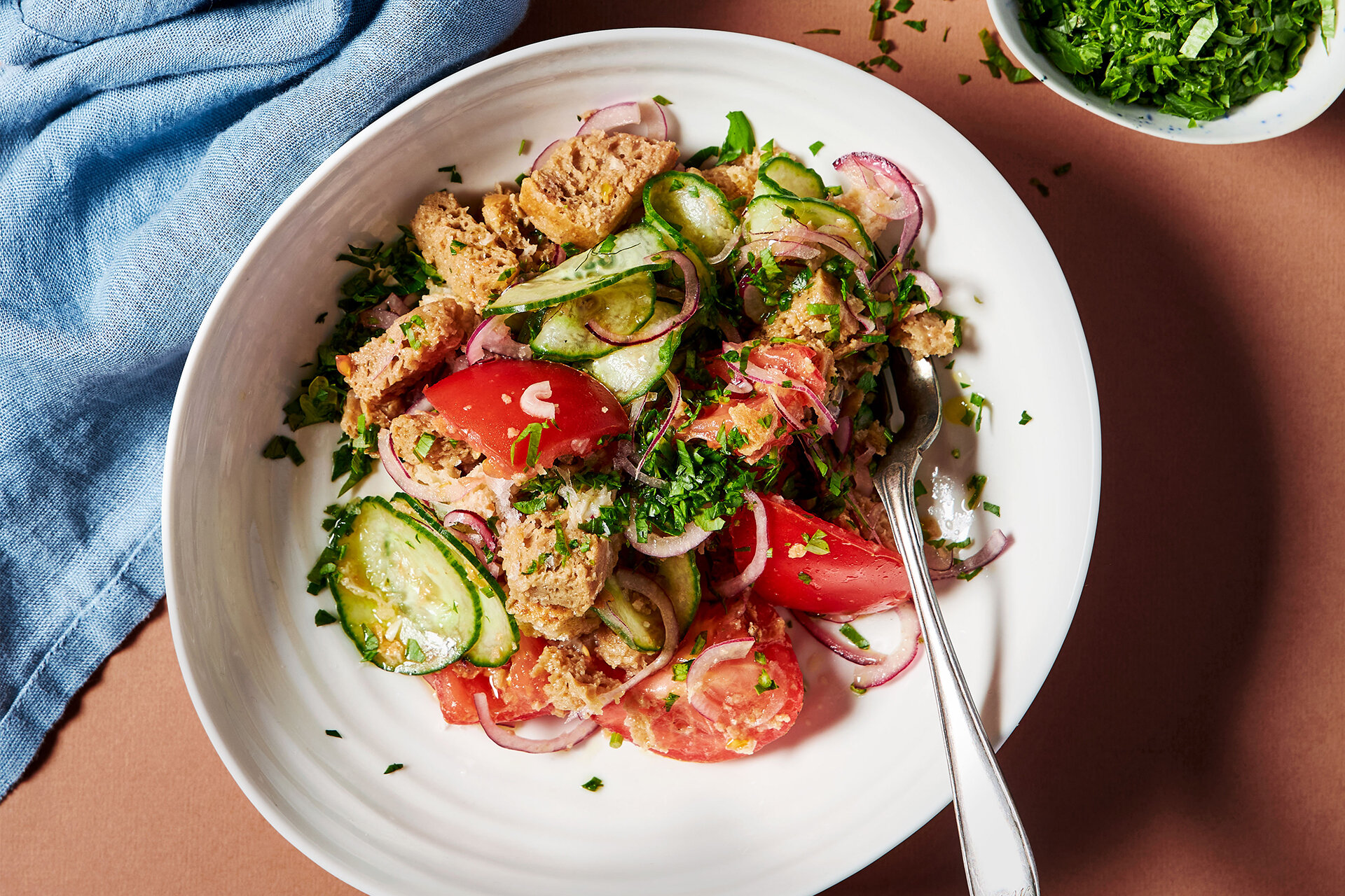 Teller mit Brotsalat, daneben Öl und Kräuter.