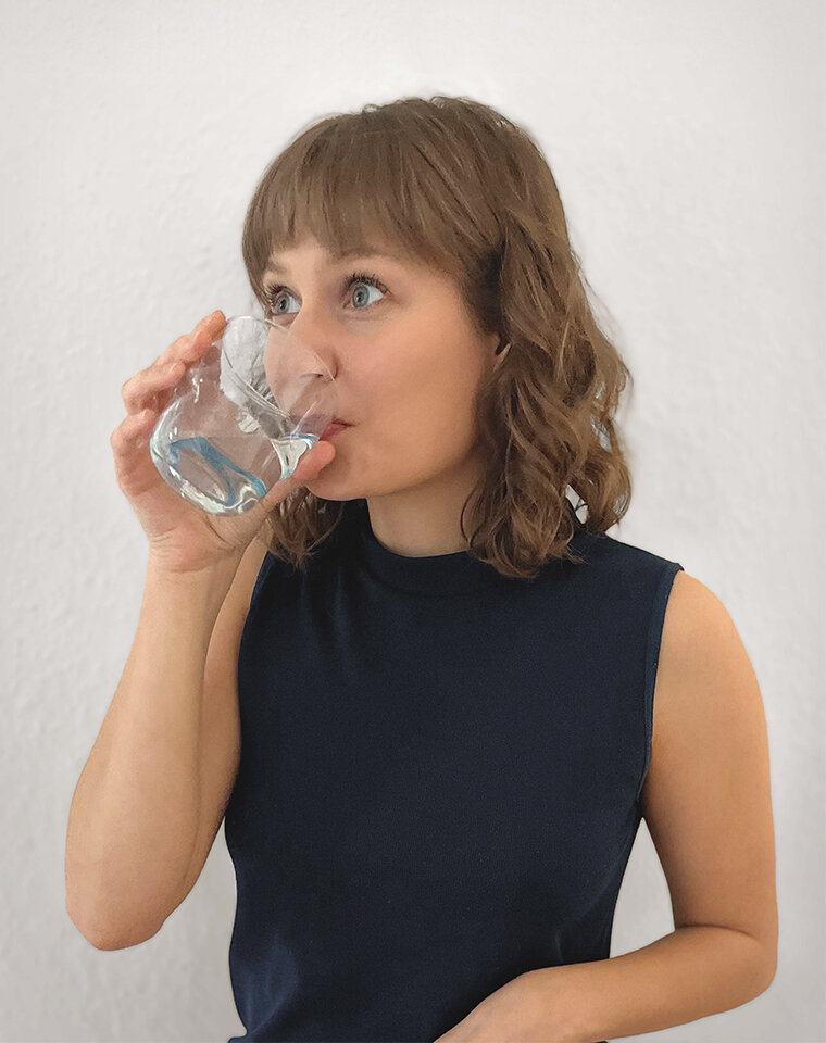 Porträt einer Frau, die ein Glas Wasser trinkt.