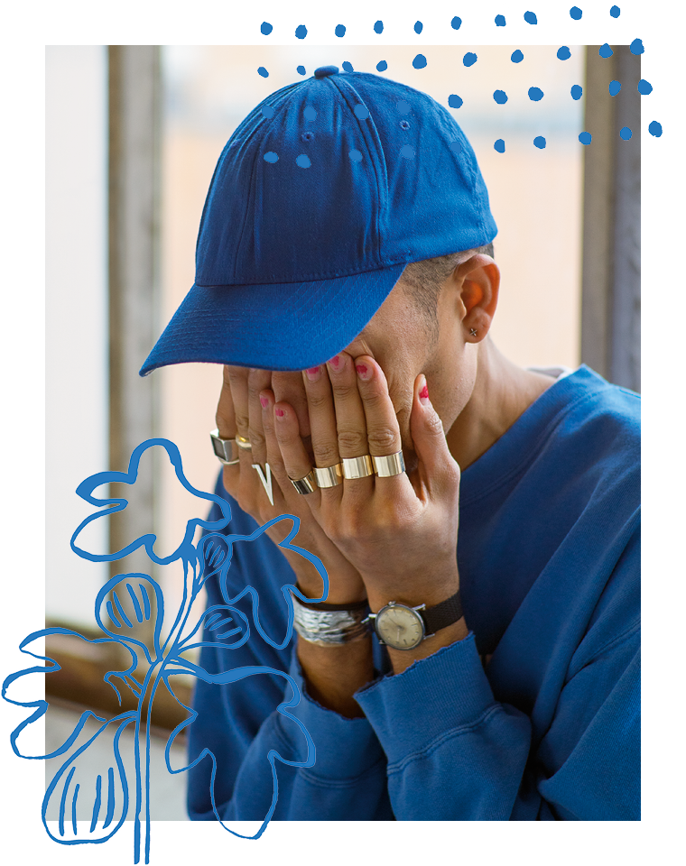 Ein Mann mit Basecap hält sich die Hände vors Gesicht. Er trägt viel Goldschmuck und lackierte Nägel.