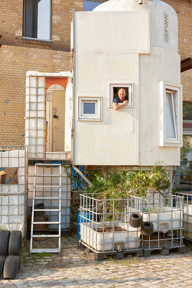 Mann schaut aus dem Fenster seines selbstgebauten Hauses, das aus einem Silo besteht.