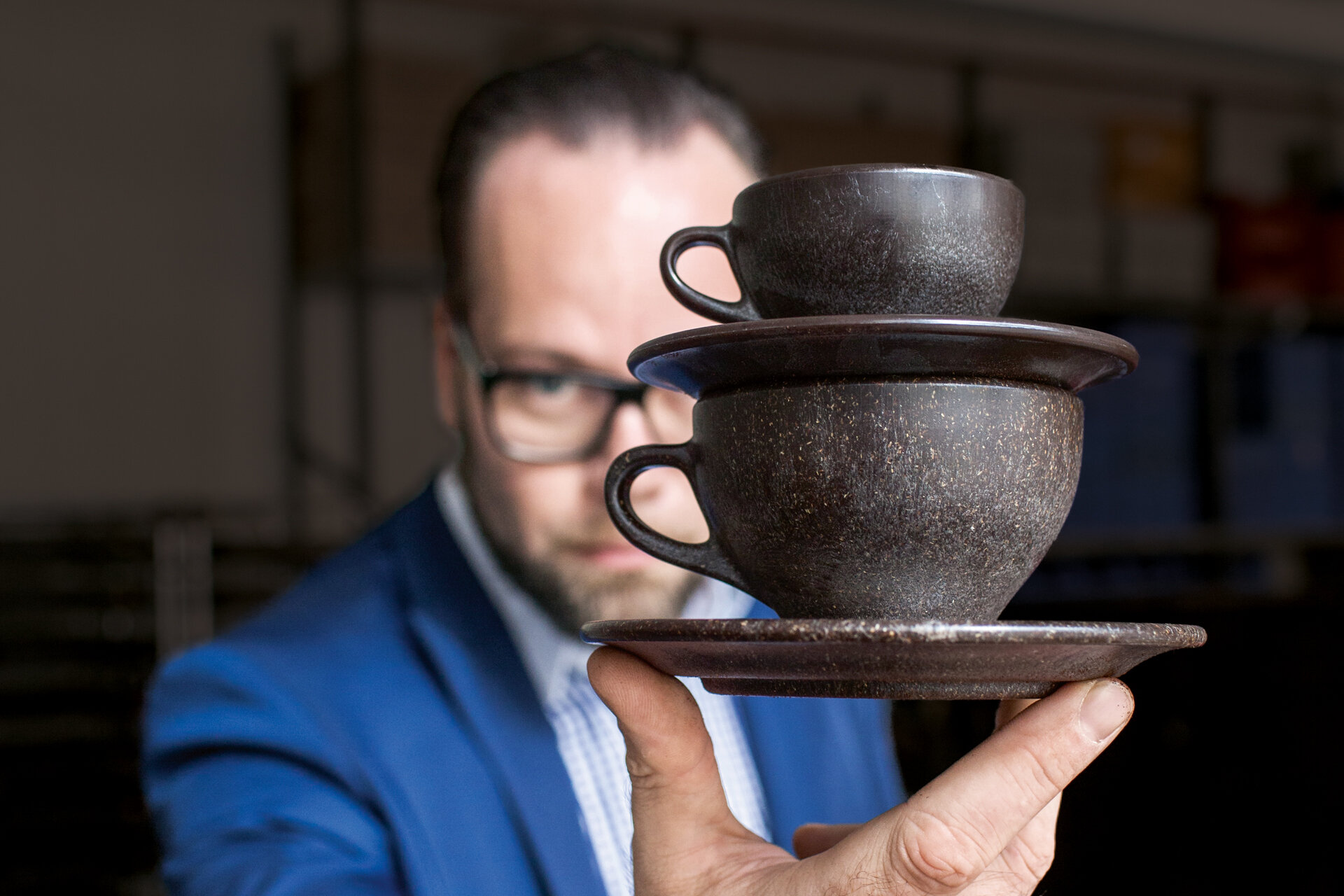 Mann hält Kaffetassen in die Kamera