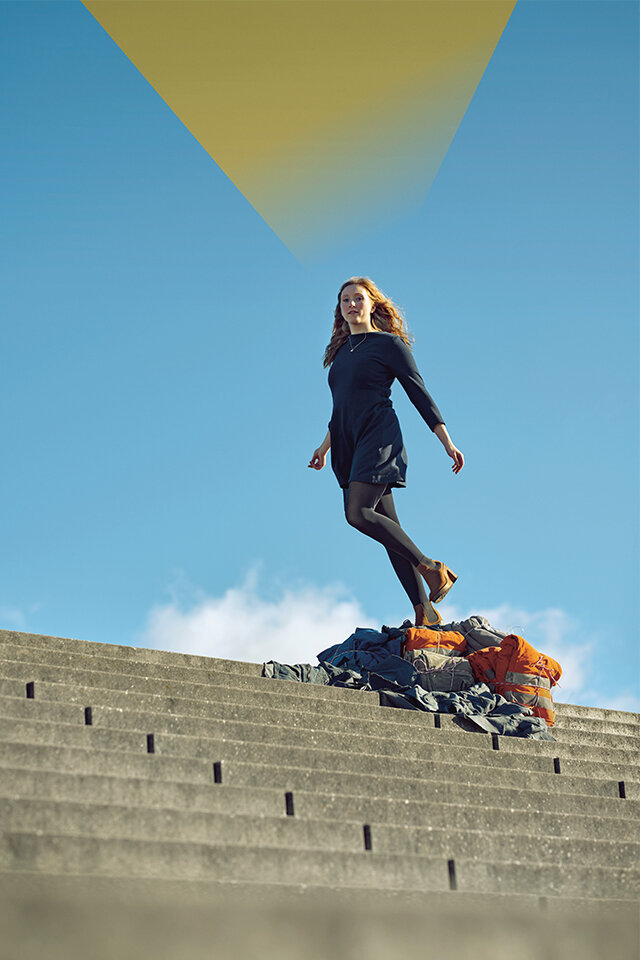 Frau in laufender Bewegung mit blauem Himmel im Hintergrund – sie wird durch ein grafisches, gelbes Element hervorgehoben.