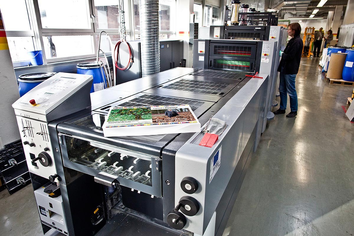 Blick in eine Druckerei: Auf einer Druckmaschine liegt ein Stapel neu gedruckter Magazinseiten.