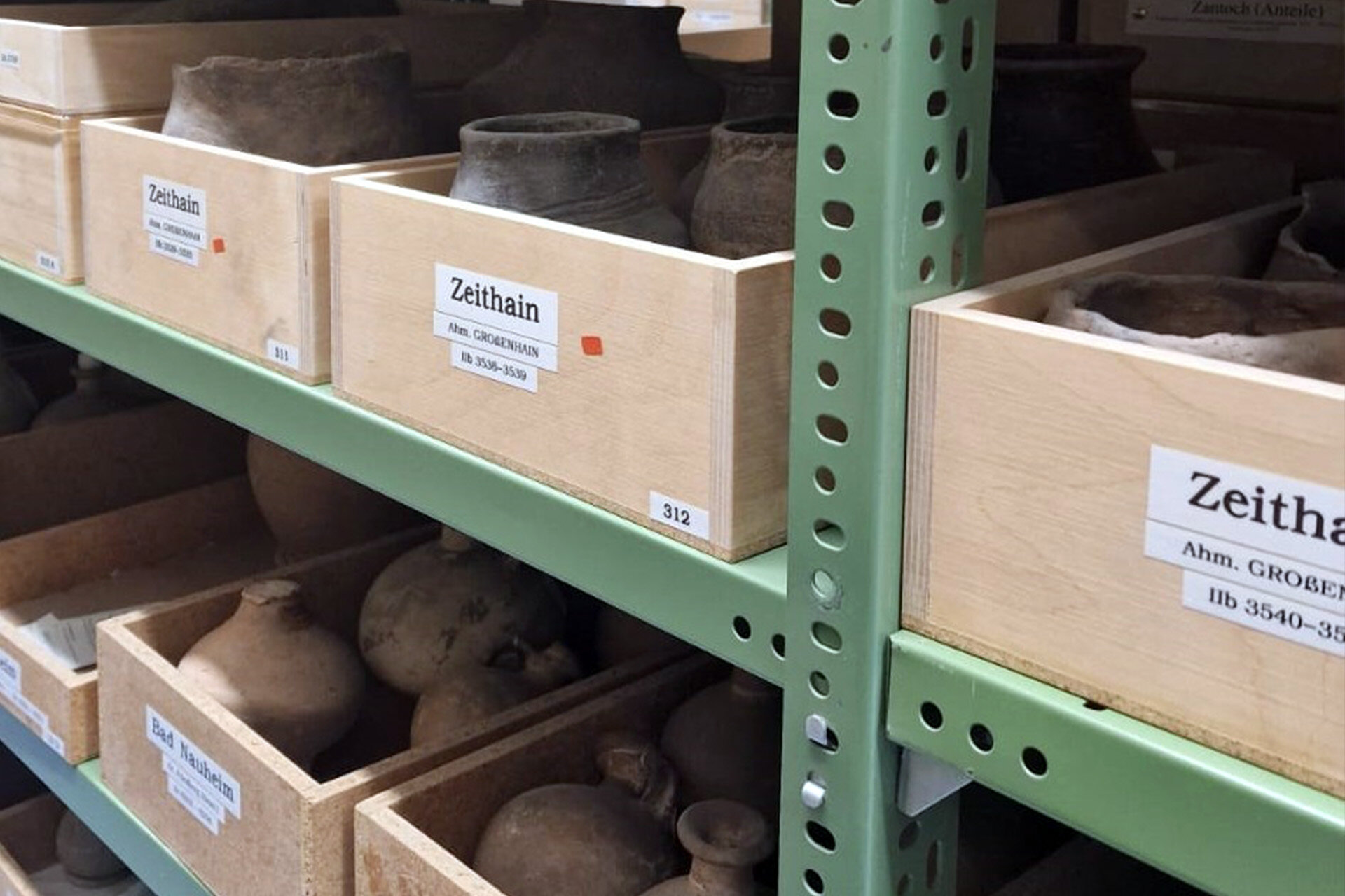 Kisten mit Geschichte, Kreativhaus: Bild eines Regals mit Kisten vom Museum für Vor- und Frühgeschichte 