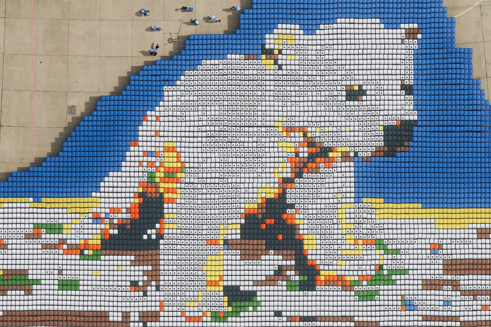Luftaufnahme von verschiedenfarbigen Mülltonnen, die zusammen einen Eisbären zeigen