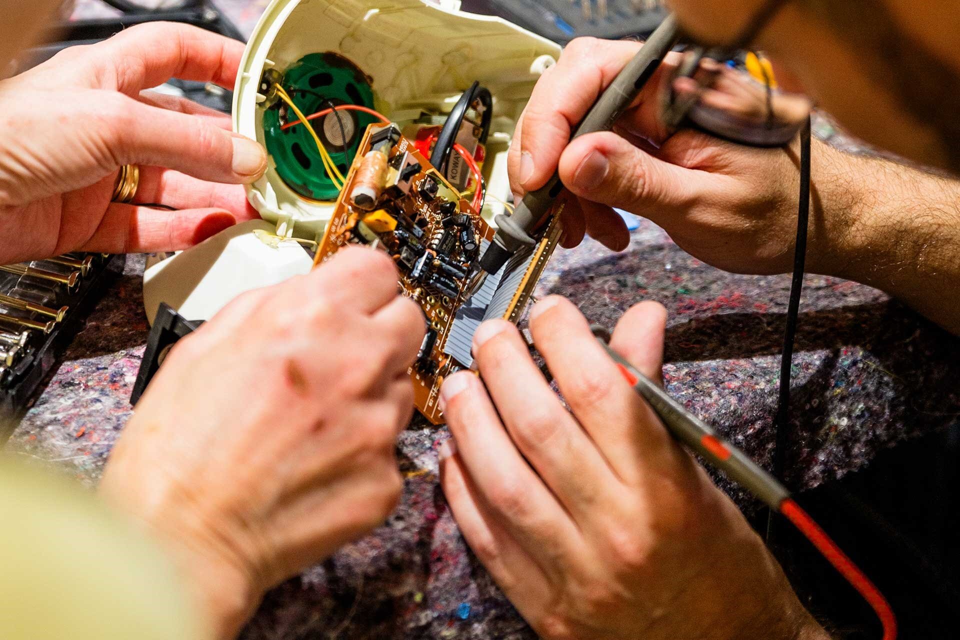 Zwei Personen reparieren ein elektronisches Bauteil